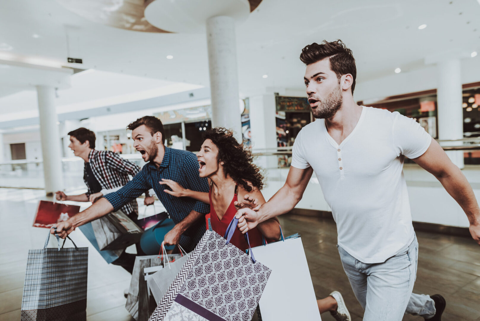 Four friends running with bags in hand shopping for a good deal.