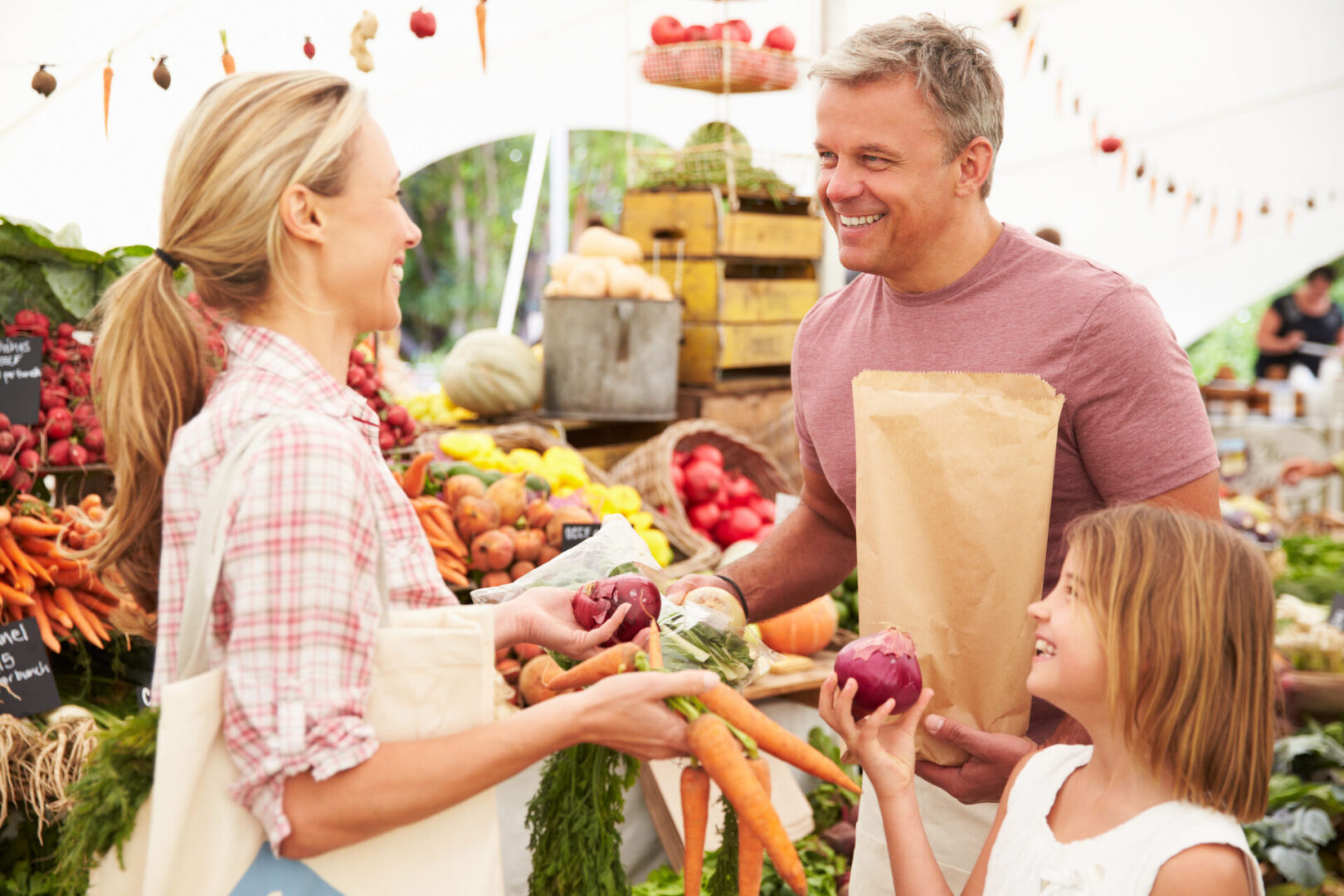 Family Buying Fresh Vegetables At Farmers Market Stall