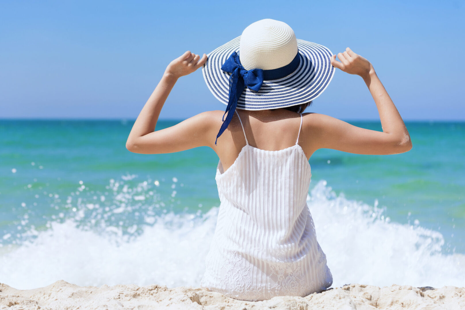 Summer time woman vacation on the beach. Cheerful woman wear summer dress and straw hats sitting on the beach look at sea.