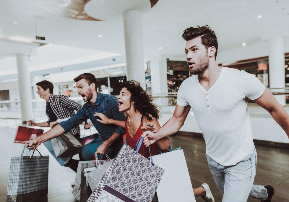 Four friends running with bags in hand shopping for a good deal.