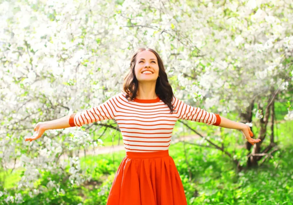 Happy pretty smiling woman enjoying flowers over spring garden background after her spring detox